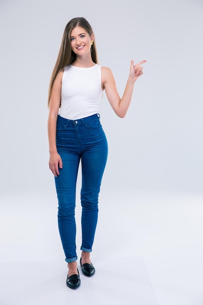 Retrato de cuerpo entero de un adolescente femenino alegre que señala el dedo lejos aislado. Mirando a la camara