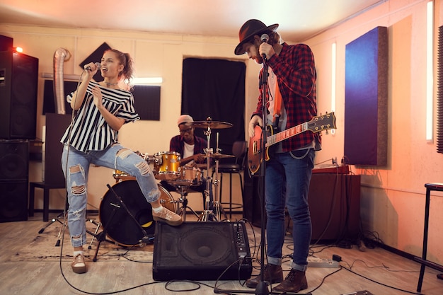 Foto retrato de cuerpo entero de la banda de música contemporánea con hermosa mujer cantando