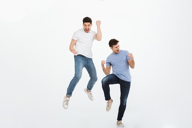 Retrato de cuerpo entero de dos jóvenes felices saltando