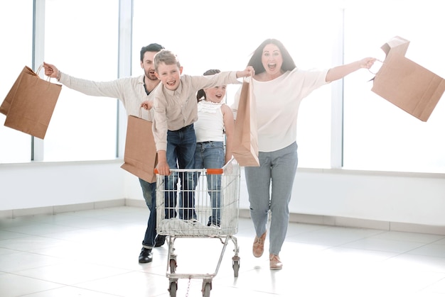 Retrato de cuerpo entero de una familia joven de pie con foto de carrito de compras con espacio de copia