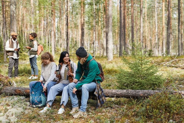 Retrato de cuerpo entero de un grupo diverso de amigos tomando un descanso mientras disfruta de una caminata en el bosque.