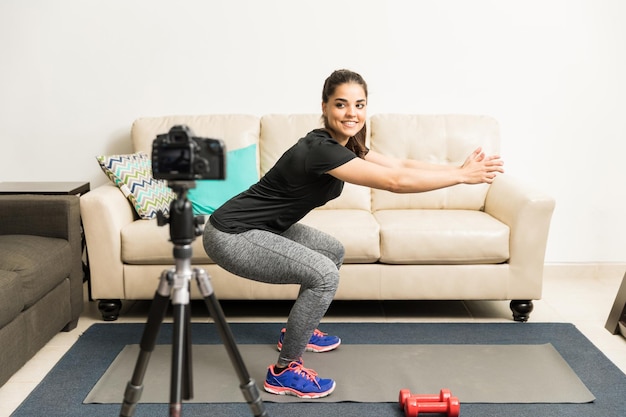 Retrato de cuerpo entero de una hermosa joven vloguera de fitness grabando un video