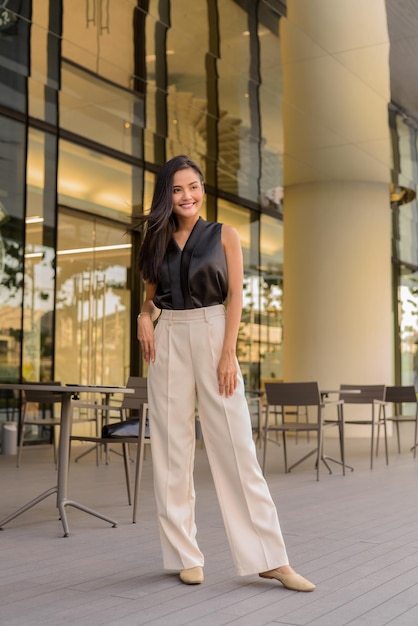 Retrato de cuerpo entero de hermosa mujer asiática al aire libre en el restaurante cafetería