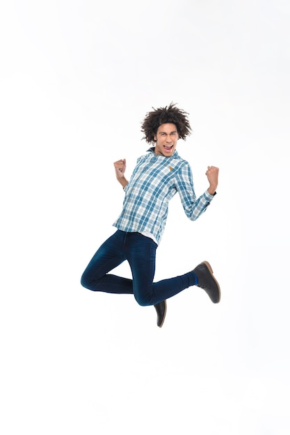 Foto retrato de cuerpo entero de un hombre afroamericano alegre saltando aislado en una pared blanca