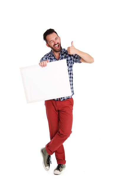 Retrato de cuerpo entero de hombre alegre con cartel en blanco y mostrando los pulgares para arriba en blanco b