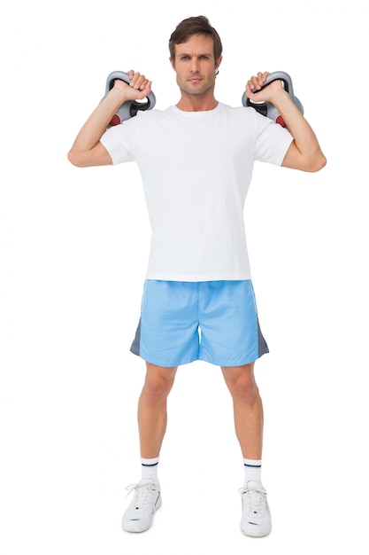 Retrato de cuerpo entero de un hombre en forma elevación kettlebells