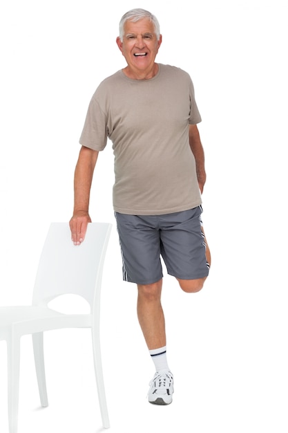 Retrato de cuerpo entero de un hombre senior feliz estirando la pierna