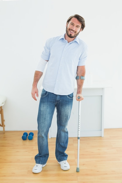 Retrato de cuerpo entero de un hombre sonriente con muleta