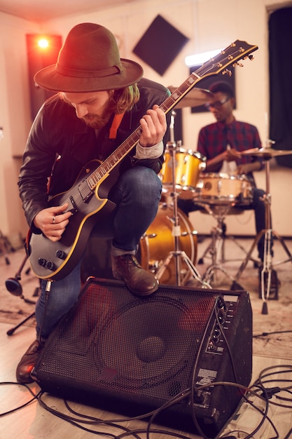 Foto retrato de cuerpo entero del joven contemporáneo tocando solo de guitarra eléctrica