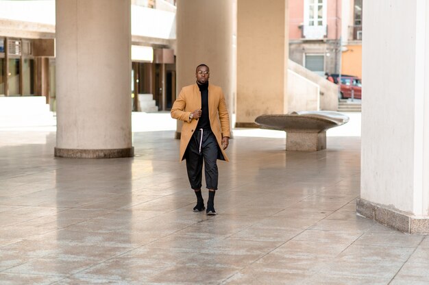 Retrato de cuerpo entero del joven empresario negro caminando en la ciudad.