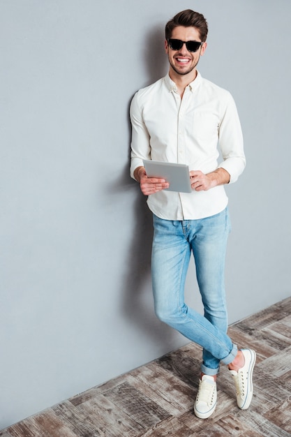 Retrato de cuerpo entero de un joven feliz con tablet PC aislado