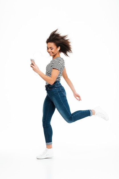 Retrato de cuerpo entero de una mujer africana despreocupada feliz saltando