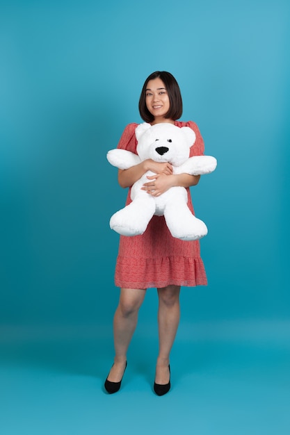 Retrato de cuerpo entero de una mujer asiática abrazando un osito de peluche blanco como regalo de San Valentín