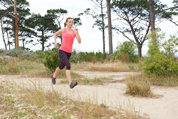 Retrato de cuerpo entero de mujer corriendo en el camino fuera