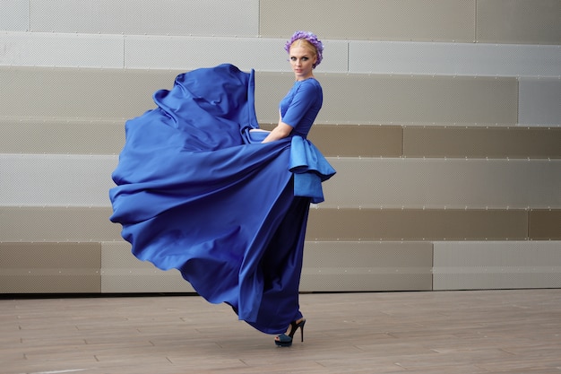 Retrato de cuerpo entero de una mujer de moda con su vestido volando en el aire