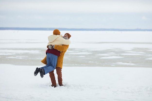 Retrato de cuerpo entero de una pareja joven despreocupada abrazándose en un espacio mínimo de copia de paisaje invernal