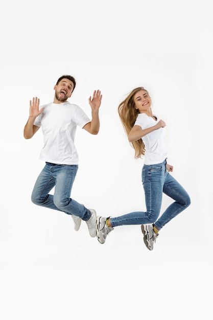 Retrato de cuerpo entero de pareja en traje casual saltando