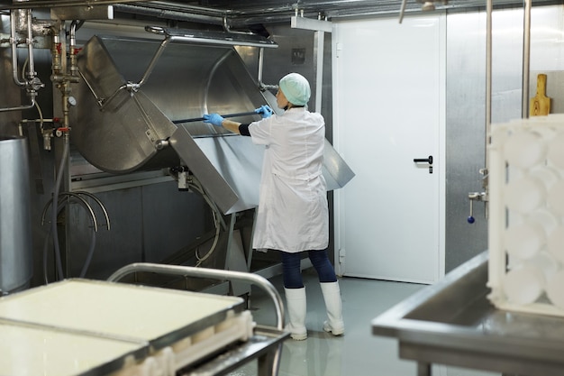 Retrato de cuerpo entero de la trabajadora lavando el tanque de cuajada en el taller de la fábrica de quesos, espacio de copia