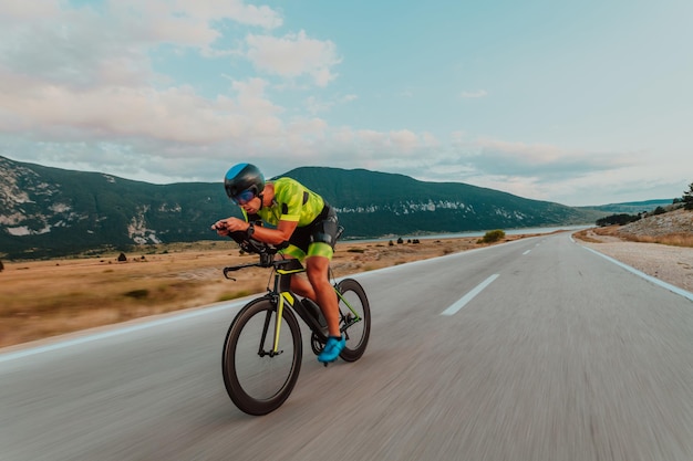 Retrato de cuerpo entero de un triatleta activo en ropa deportiva y con casco protector andando en bicicleta. Enfoque selectivo.