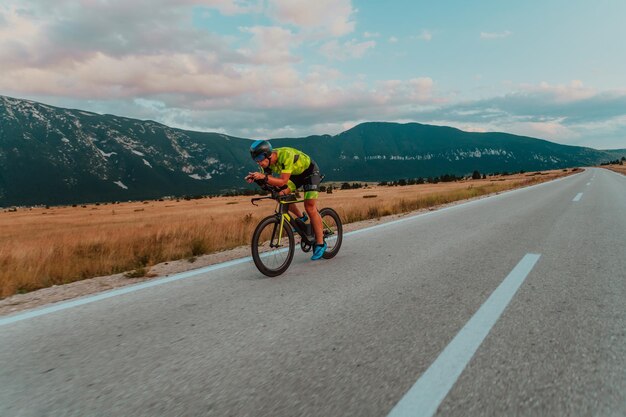 Retrato de cuerpo entero de un triatleta activo en ropa deportiva y con casco protector andando en bicicleta. Enfoque selectivo.