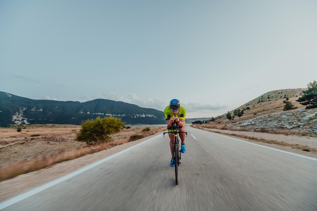 Retrato de cuerpo entero de un triatleta activo en ropa deportiva y con casco protector andando en bicicleta. Enfoque selectivo.