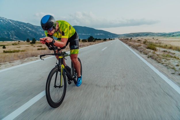 Retrato de cuerpo entero de un triatleta activo en ropa deportiva y con casco protector andando en bicicleta. Enfoque selectivo.