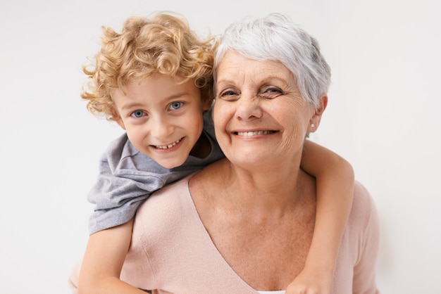 Retrato a cuestas y abuela con niño se abrazan felices y se unen contra un fondo de pared Cara de amor y mujer mayor con nieto divirtiéndose abrazando y disfrutando el fin de semana juntos