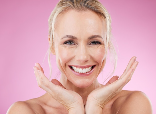 Retrato de cuidado de la piel de mujer con sonrisa y manos piel brillante con maquillaje de spa natural en estudio Publicidad de maquetas y cosméticos de lujo de belleza cara de modelo feliz aislado sobre fondo rosa