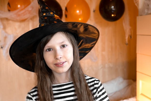 Foto retrato da adorável menina adolescente usando chapéu de halloween, dançando e sorrindo, festa familiar de halloween