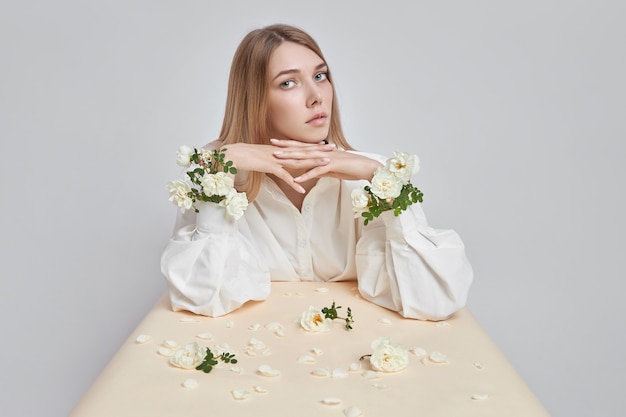 Retrato da arte da beleza de uma mulher com flores rosas nas mãos. cosméticos naturais para mãos e rosto