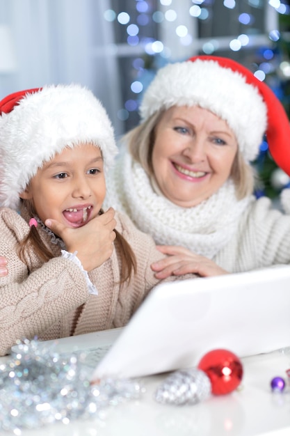 Retrato da avó e da neta usando laptop no Natal em casa