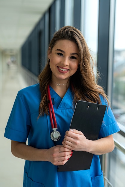 Retrato da bela enfermeira em uniforme azul com área de transferência no hospital moderno. conceito médico