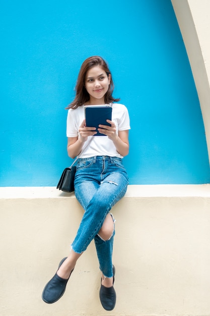 Retrato da bela estudante universitária está sorrindo no fundo da parede azul