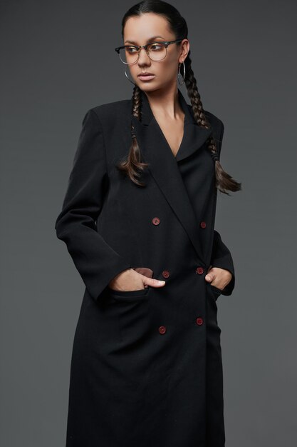 Retrato da bela garota hispânica encantadora no casaco preto comprido