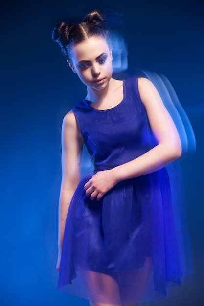 Retrato da bela jovem modelo posando com vestido azul contra fundo azul.