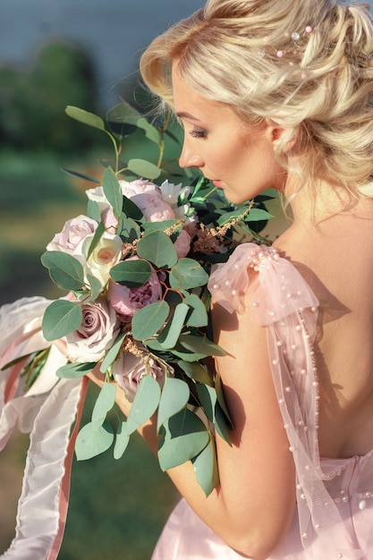 Retrato da bela noiva com buquê de flores na natureza. fotografia de belas artes.