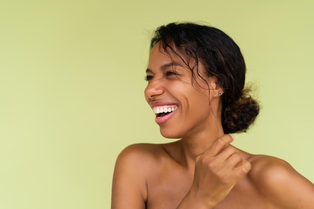 Retrato da beleza da jovem mulher afro-americana em topless com ombros nus sobre fundo verde com pele perfeita e maquiagem natural