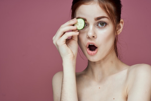 Retrato da beleza da menina com pepinos em um fundo rosa procedimentos de beleza