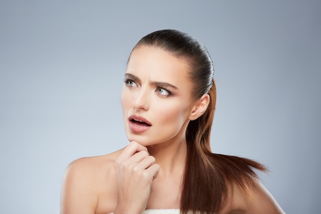 Foto retrato da beleza da menina olhando de lado pensando em algo. cabeça e ombros de mulher séria tocando seu lábio inferior. maquilhagem natural, estúdio, verdadeiras emoções