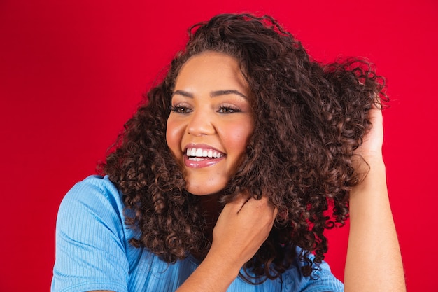 Retrato da beleza da mulher afro-americana com penteado afro e maquiagem de glamour. mulher brasileira. mestiço. cabelo encaracolado. estilo de cabelo. fundo vermelho.