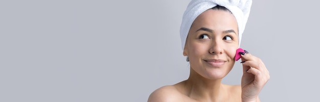 Retrato da beleza da mulher na toalha branca na cabeça com uma esponja para um corpo em vista de um coração rosa Skincare limpeza eco spa cosmético orgânico relaxar conceito