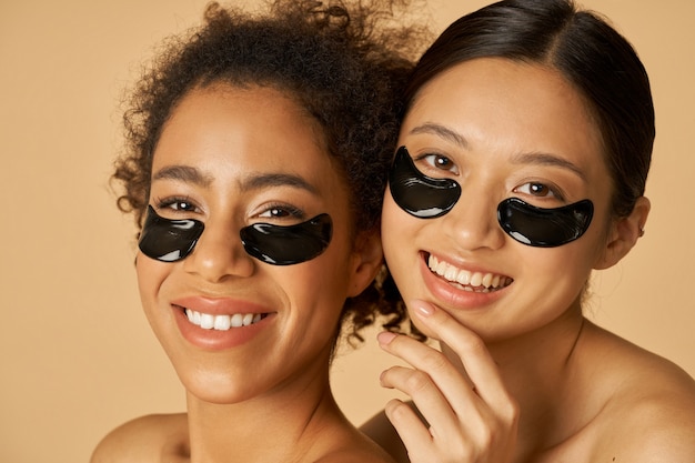 Retrato da beleza de duas jovens animadas posando com tapa-olho preto aplicado