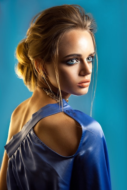 Retrato da beleza de mulher elegante com penteado elegante e maquiagem com vestido azul