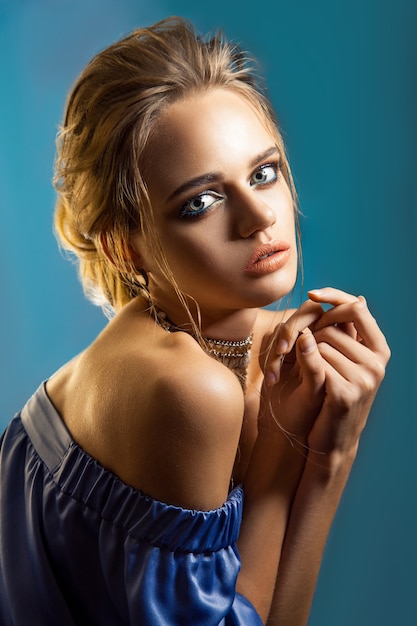 Retrato da beleza de mulher elegante com penteado elegante e maquiagem com vestido azul