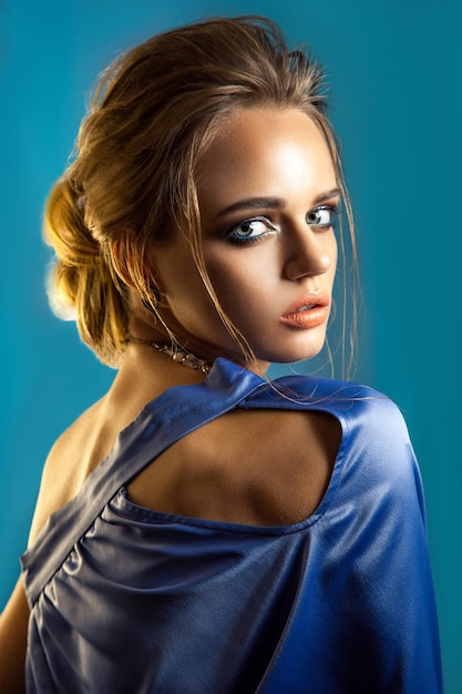 Retrato da beleza de mulher elegante com penteado elegante e maquiagem com vestido azul