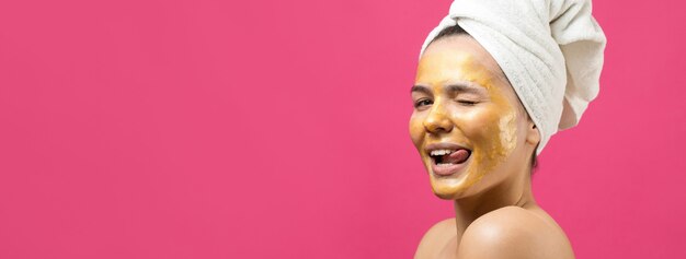Retrato da beleza de mulher em uma toalha branca na cabeça com máscara nutritiva de ouro no rosto. skincare cleansing eco orgânico cosmético spa relaxa conceito.