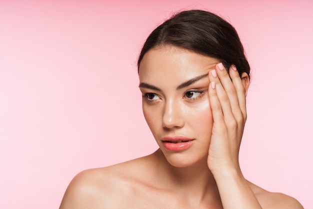 Foto retrato da beleza de uma bela jovem morena de topless em pé isolado na rosa, posando