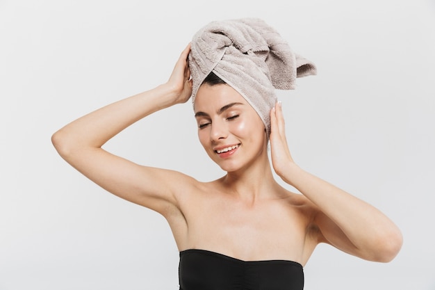 Retrato da beleza de uma jovem atraente isolada sobre uma parede branca, com uma toalha na cabeça