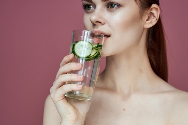 Retrato da beleza de uma jovem com um copo de água e uma pele clara de pepino