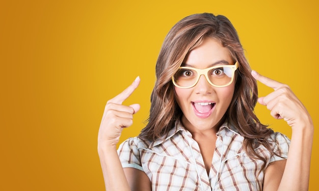 Retrato da beleza de uma jovem feliz em óculos e vestido amarelo brilhante sobre fundo amarelo.